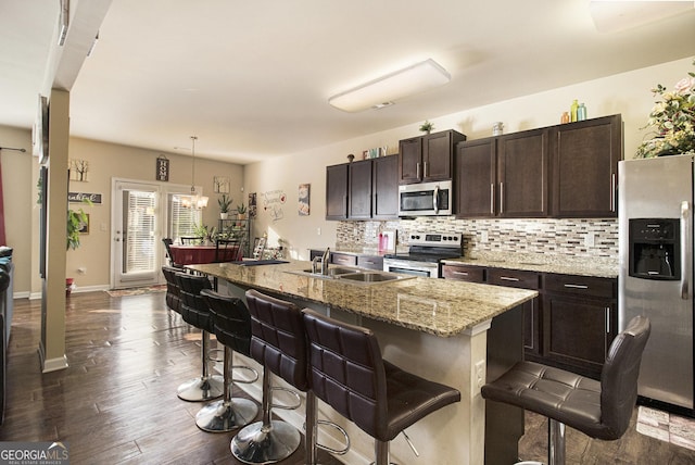 kitchen featuring a sink, appliances with stainless steel finishes, dark brown cabinetry, and backsplash