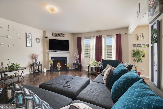 living area with baseboards, a warm lit fireplace, and wood finished floors