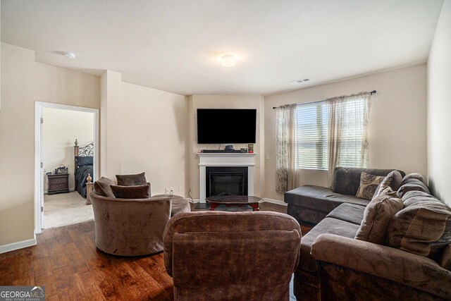 living room with visible vents, dark wood finished floors, a glass covered fireplace, and baseboards