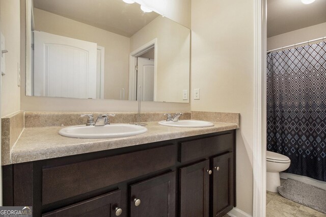 full bath with double vanity, toilet, and a sink