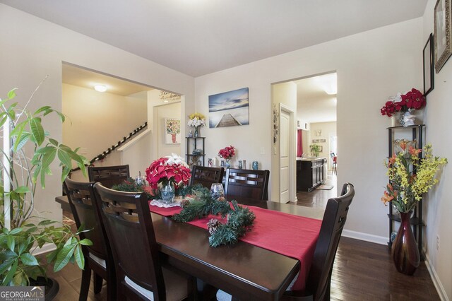 dining area with baseboards, wood finished floors, and stairway