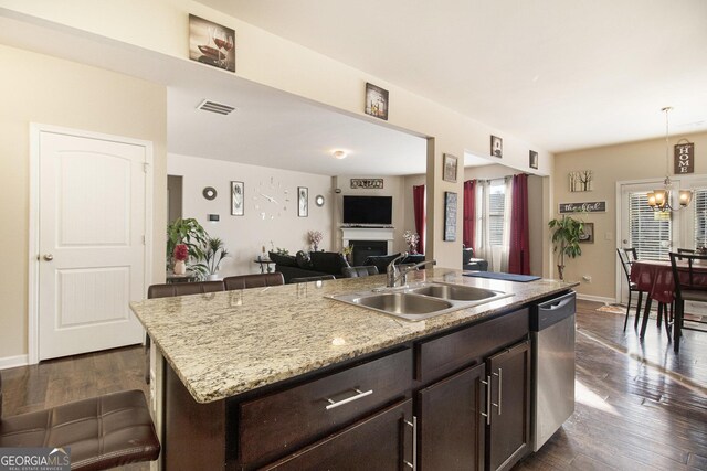 kitchen featuring visible vents, dark brown cabinets, a sink, dishwasher, and a chandelier