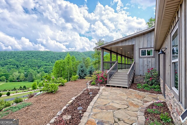 view of yard with a forest view, a patio area, and a wooden deck