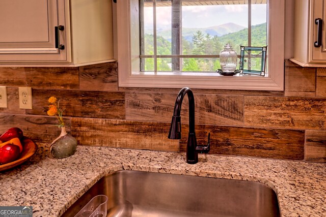 kitchen view of a sink, decorative backsplash, and light stone countertops