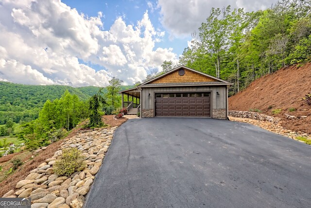 garage featuring driveway and a forest view