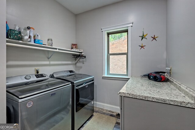 clothes washing area with washer and clothes dryer, light wood-type flooring, and baseboards