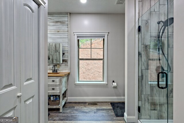 full bath featuring baseboards, a stall shower, wood finished floors, and vanity