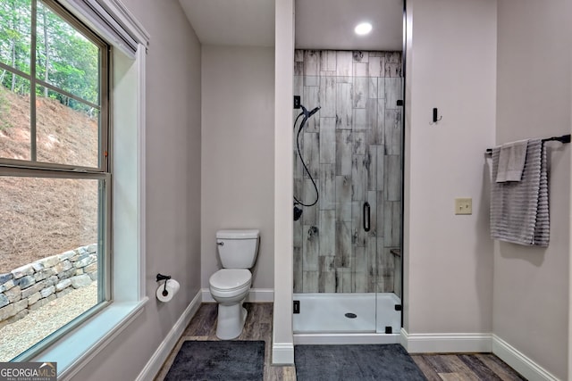 full bath featuring a stall shower, toilet, wood finished floors, baseboards, and recessed lighting