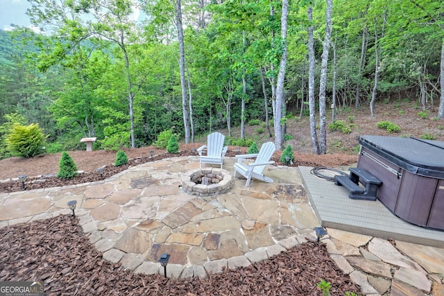 view of patio / terrace with a hot tub and an outdoor fire pit