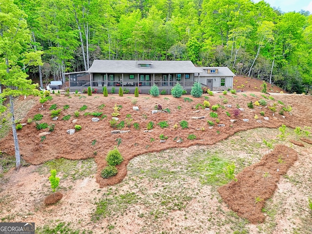 ranch-style home with covered porch and a wooded view