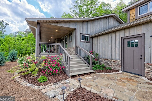 property entrance with board and batten siding and stone siding