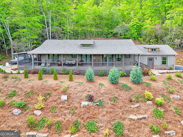 view of front of property with covered porch, a shingled roof, a view of trees, and board and batten siding