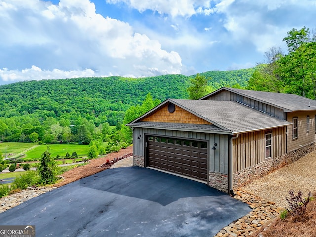 garage with a wooded view and asphalt driveway