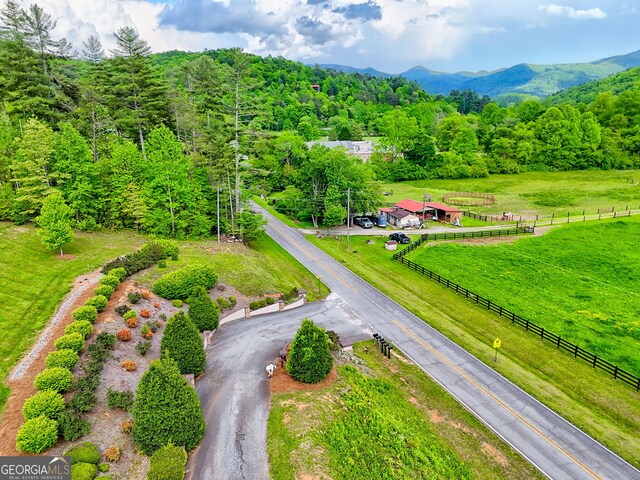 view of rural area with a mountain backdrop and a heavily wooded area