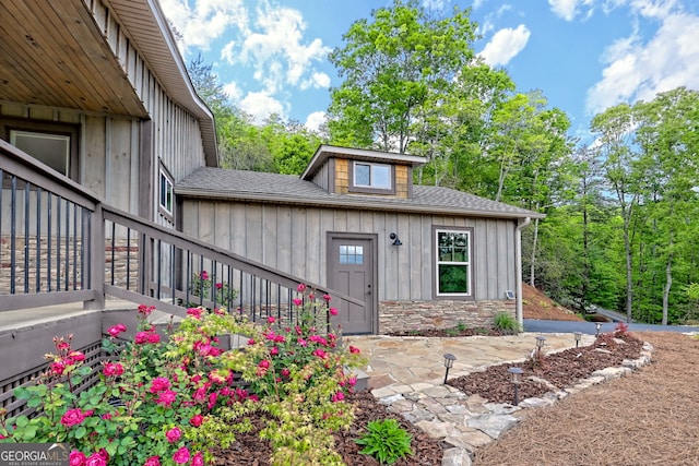 property entrance with board and batten siding and roof with shingles