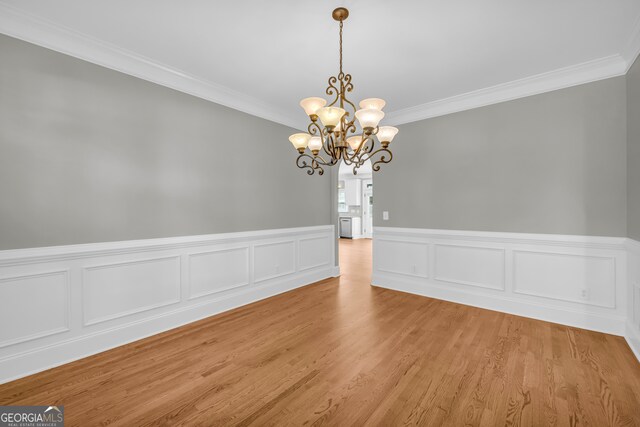 3641 Carriage Glen Way, Dacula, GA 30019 - empty room featuring ornamental molding, a chandelier, light wood-style floors, and a wainscoted wall