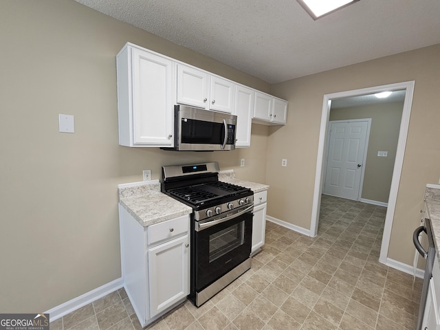 kitchen with white cabinetry, baseboards, appliances with stainless steel finishes, and a textured ceiling
