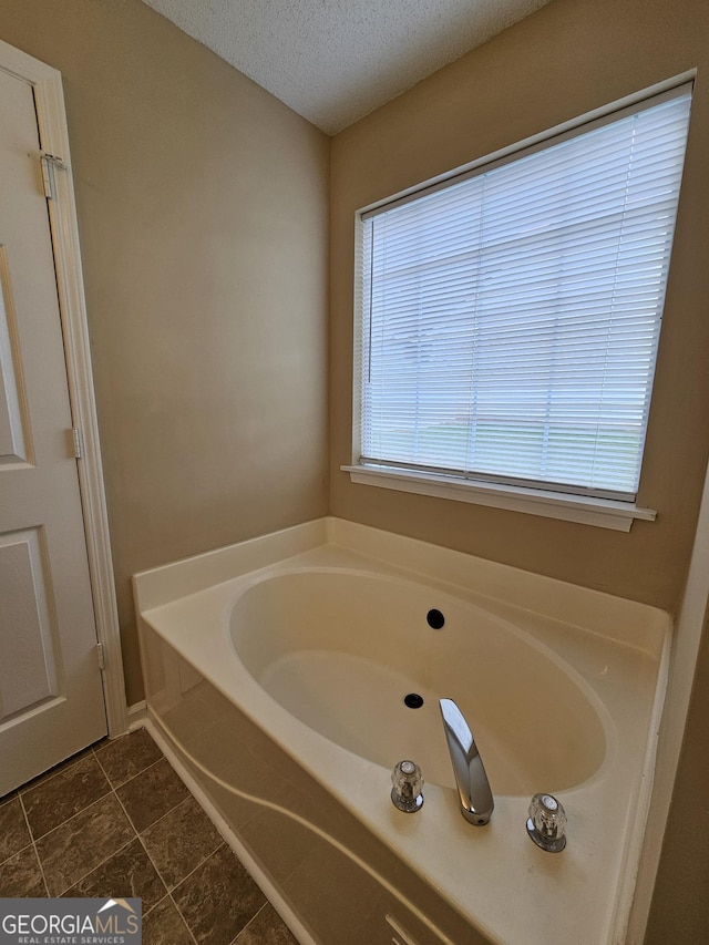 bathroom featuring a textured ceiling, tile patterned flooring, and a bath