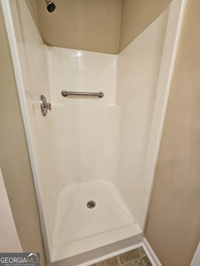 full bathroom with tile patterned floors, walk in shower, and baseboards