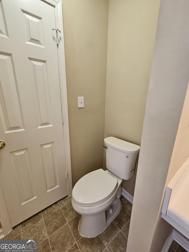 bathroom featuring baseboards, tile patterned floors, and toilet