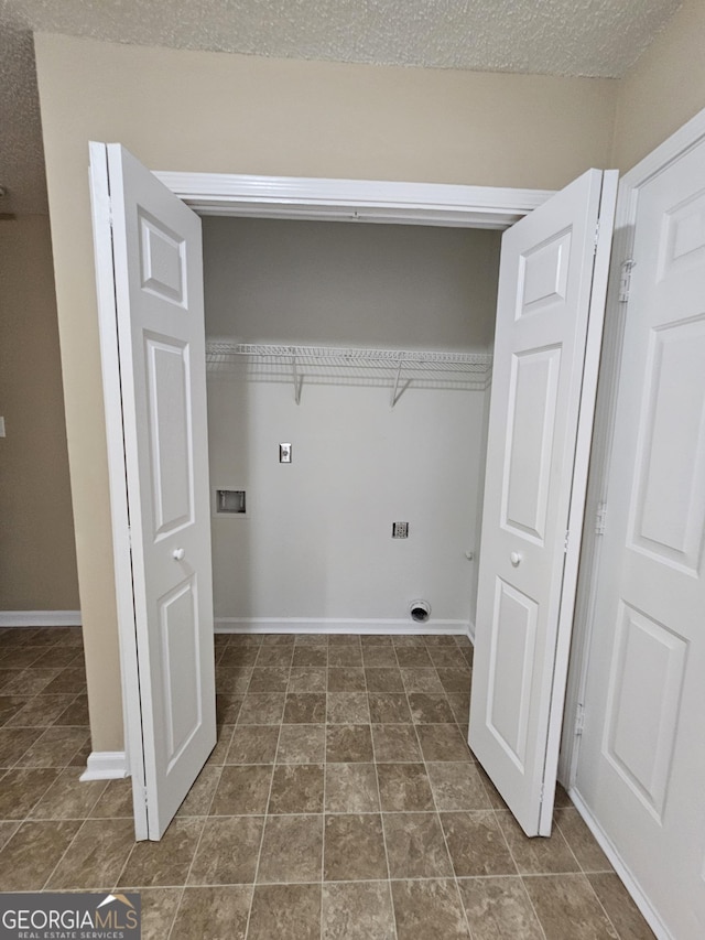 clothes washing area featuring dark tile patterned flooring, laundry area, baseboards, and hookup for a washing machine