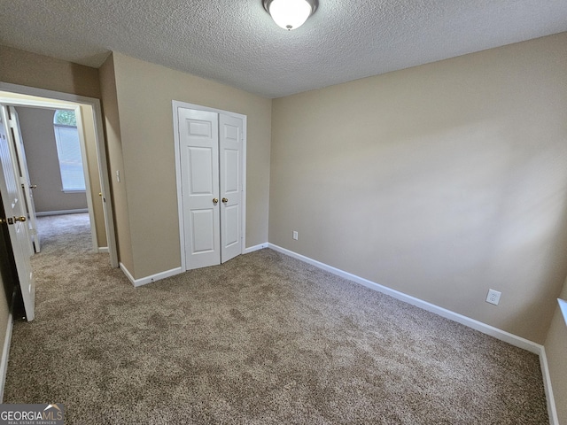 unfurnished bedroom featuring a closet, a textured ceiling, and carpet