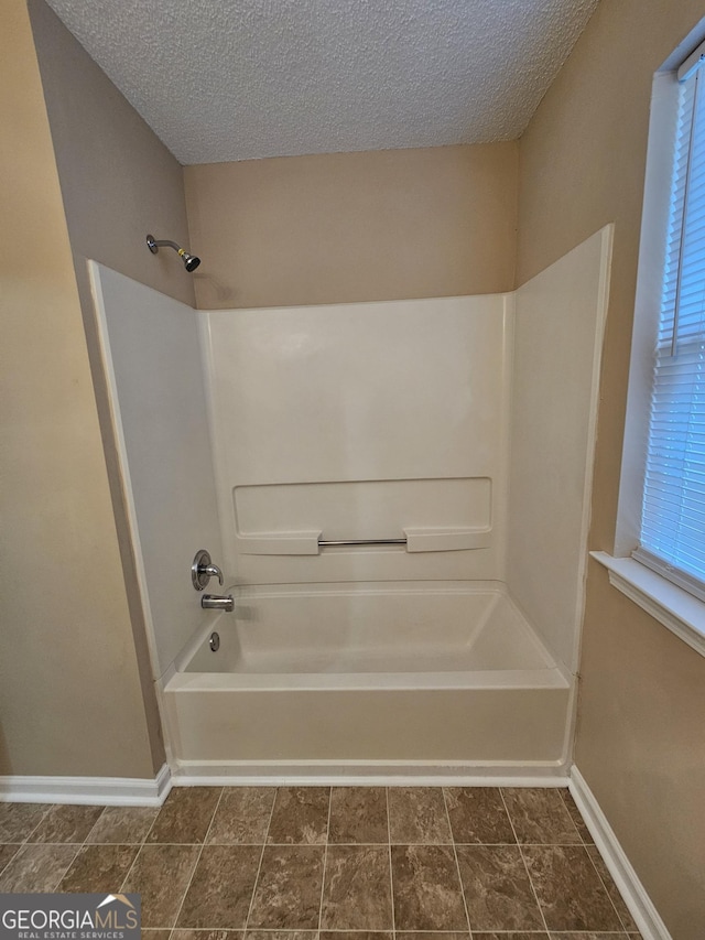 full bathroom featuring baseboards, a textured ceiling, bathtub / shower combination, and a healthy amount of sunlight