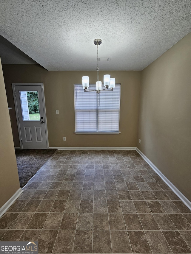 unfurnished dining area featuring a textured ceiling, an inviting chandelier, and baseboards