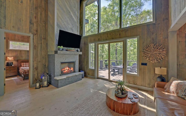 living room featuring a high ceiling, a fireplace, and wood walls