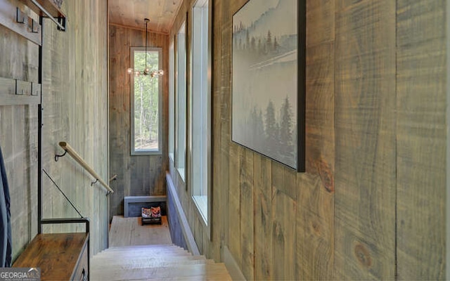 hall featuring wood walls, lofted ceiling, a chandelier, and wooden ceiling