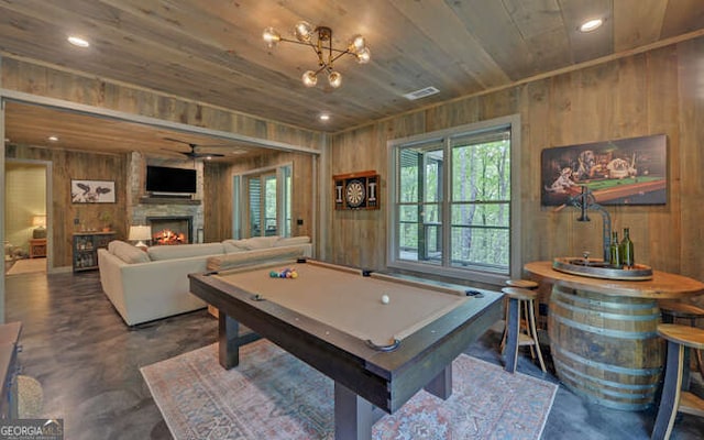 recreation room with wooden walls, wooden ceiling, concrete floors, and plenty of natural light
