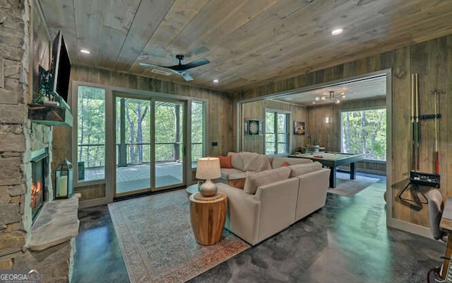 living room featuring concrete flooring, wood walls, wood ceiling, and a fireplace