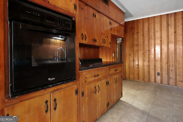 4365 US Highway 341, Jesup, GA 31545 - kitchen featuring black oven, brown cabinets, wooden walls, dark countertops, and light tile patterned flooring