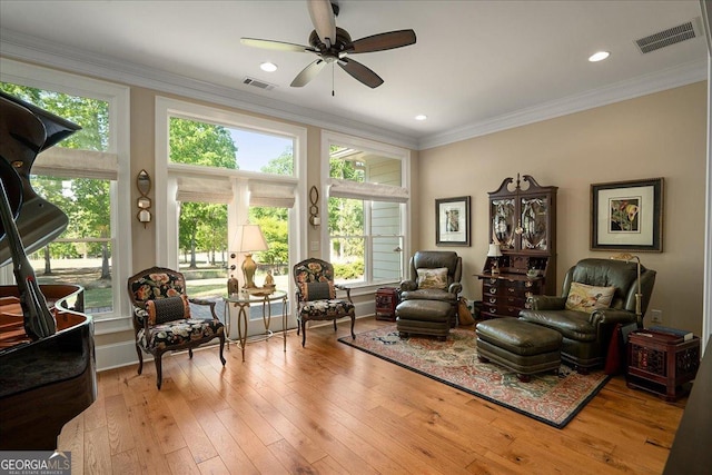 living area featuring ornamental molding, a ceiling fan, hardwood / wood-style floors, and visible vents
