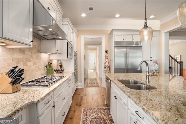 kitchen featuring visible vents, ornamental molding, built in appliances, under cabinet range hood, and a sink