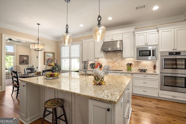 kitchen with a kitchen breakfast bar, visible vents, appliances with stainless steel finishes, under cabinet range hood, and white cabinetry