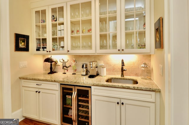 bar featuring wine cooler, baseboards, tasteful backsplash, a sink, and wet bar