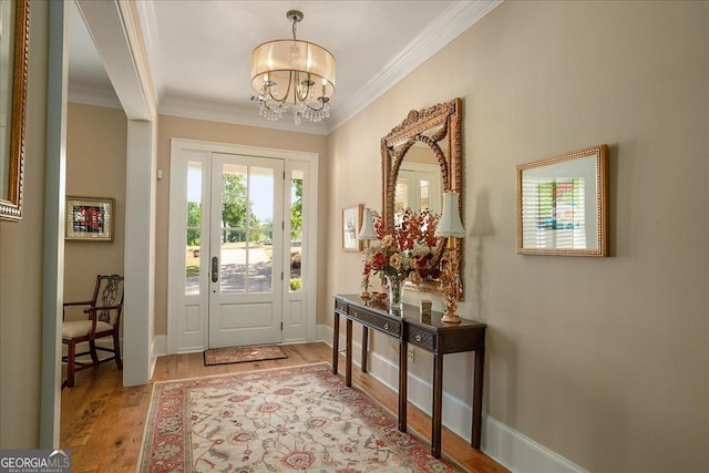 entrance foyer featuring baseboards, a notable chandelier, ornamental molding, and wood finished floors