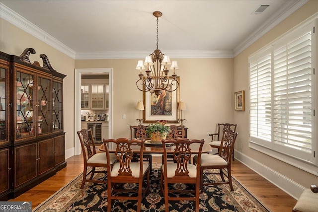 dining space featuring beverage cooler, a chandelier, ornamental molding, and visible vents