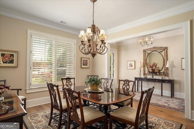 dining space featuring visible vents, crown molding, wood finished floors, baseboards, and a notable chandelier