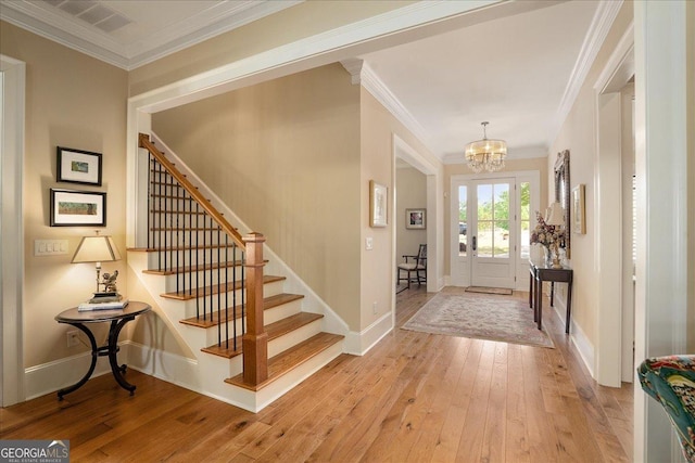 entrance foyer featuring stairway, ornamental molding, wood-type flooring, and a chandelier