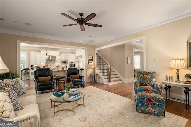 living room featuring ornamental molding, ceiling fan, wood finished floors, and stairway