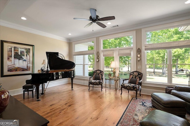 living area featuring plenty of natural light, a ceiling fan, crown molding, and hardwood / wood-style flooring