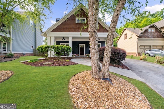 craftsman-style house featuring covered porch, concrete driveway, a front lawn, and a ceiling fan