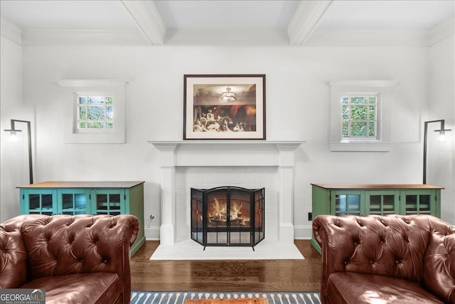 living area featuring a fireplace, ornamental molding, beam ceiling, and wood finished floors