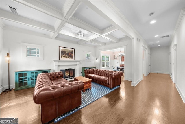 living area with a lit fireplace, baseboards, visible vents, and wood finished floors