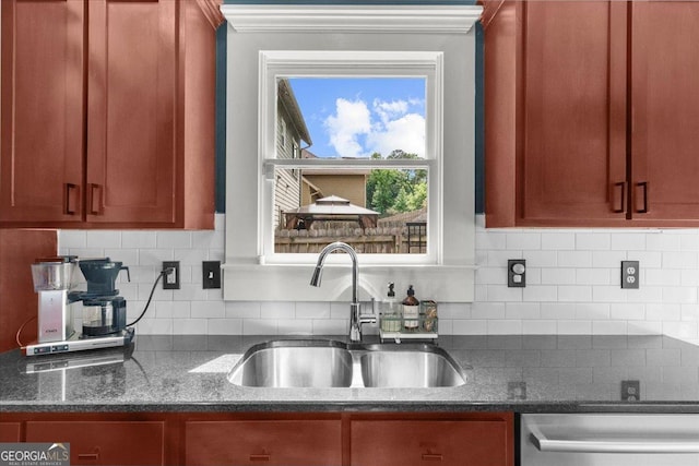 kitchen featuring dark stone countertops, a sink, dishwasher, tasteful backsplash, and ornamental molding