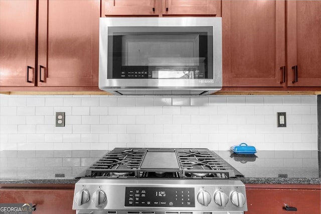 kitchen with stainless steel appliances, decorative backsplash, and dark stone countertops
