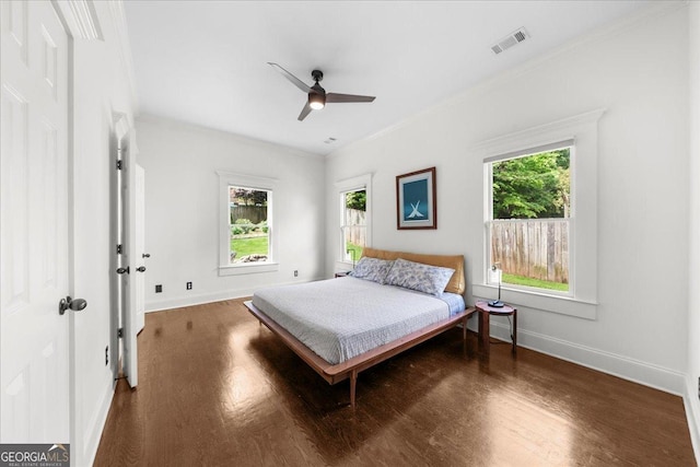 bedroom featuring baseboards, crown molding, visible vents, and wood finished floors