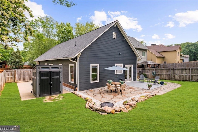 back of house featuring a yard, an outdoor structure, a patio, a shed, and a fenced backyard